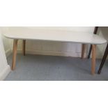 A 1970s design coffee table, the painted lozenge shaped top raised on light oak legs  18"h  49"w