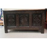 An early 20thC oak coffer with straight sides and a hinged lid, over a carved tri-panelled front,