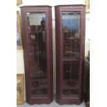 A pair of modern mahogany finished corner cabinets, each with a full height glazed door enclosing