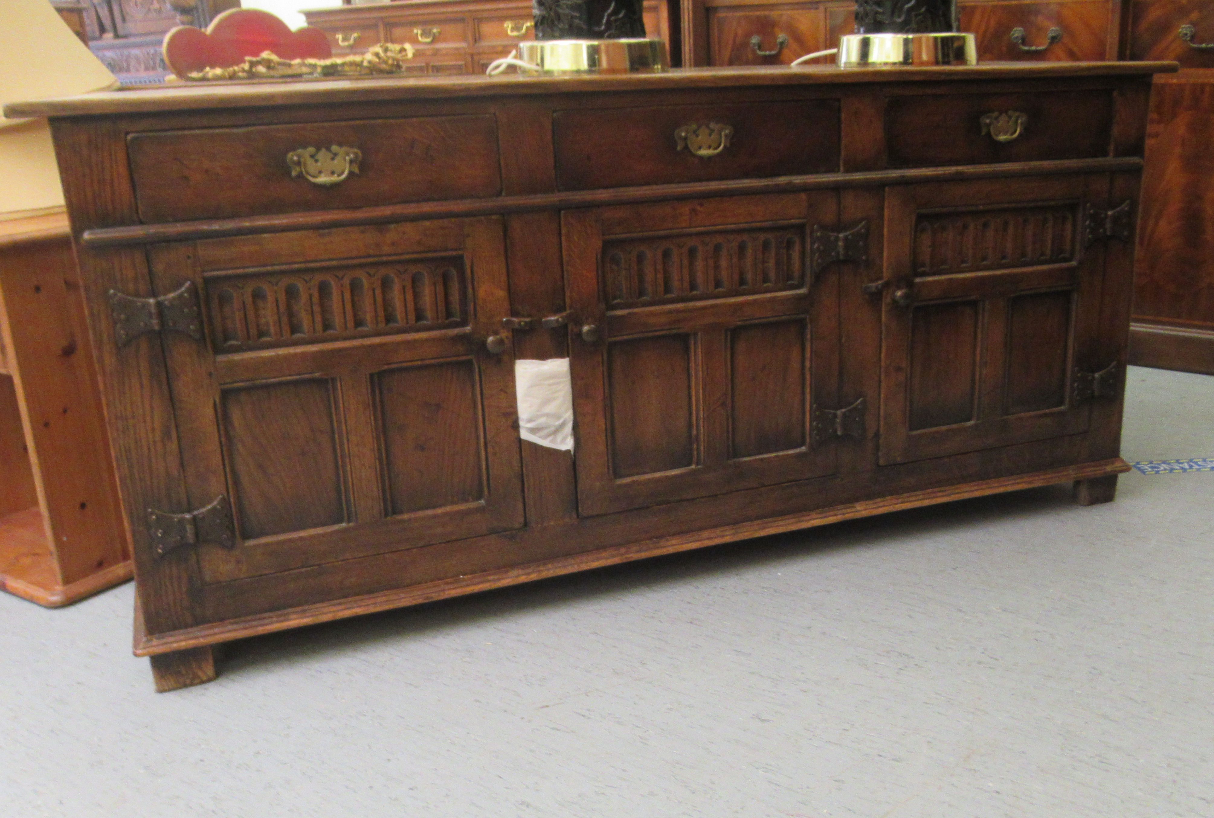 A Titchmarsh & Goodwin Old English style carved and panelled oak sideboard, comprising three