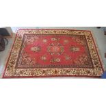 A Persian design rug, decorated with floral motifs, on a red ground  84" x 55"