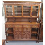A mid 20thC carved oak dresser, the panelled back and pillared superstructure with four inline