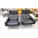 A pair of modern reclined armchairs with angled backs, part button upholstered in cushioned black