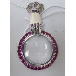 A silver and ruby set pendant magnifying glass, in the form of a hand, on a fine neckchain