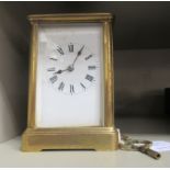 An early 20thC lacquered brass cased carriage clock with bevelled glass panels and a folding top
