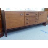 A 1970s teak finished sideboard with a central bank of three drawers, flanked by a pair of doors,