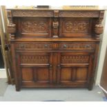A 1920s/30s carved oak court cupboard, the frieze drawer over a pair of recessed doors and outset