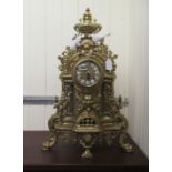 A 20thC copy of a Louis XV brass cased mantel clock with an urn finial, demonic mask and foliate