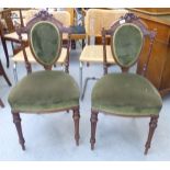 A pair of late Victorian walnut framed salon chairs with a circular green upholstered back pad and