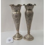 A pair of early 20thC Indian silver coloured metal vases, each of trumpet design, on a circular foot