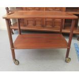 A 1970s teak two tier serving trolley, raised on casters  23"h  28"w