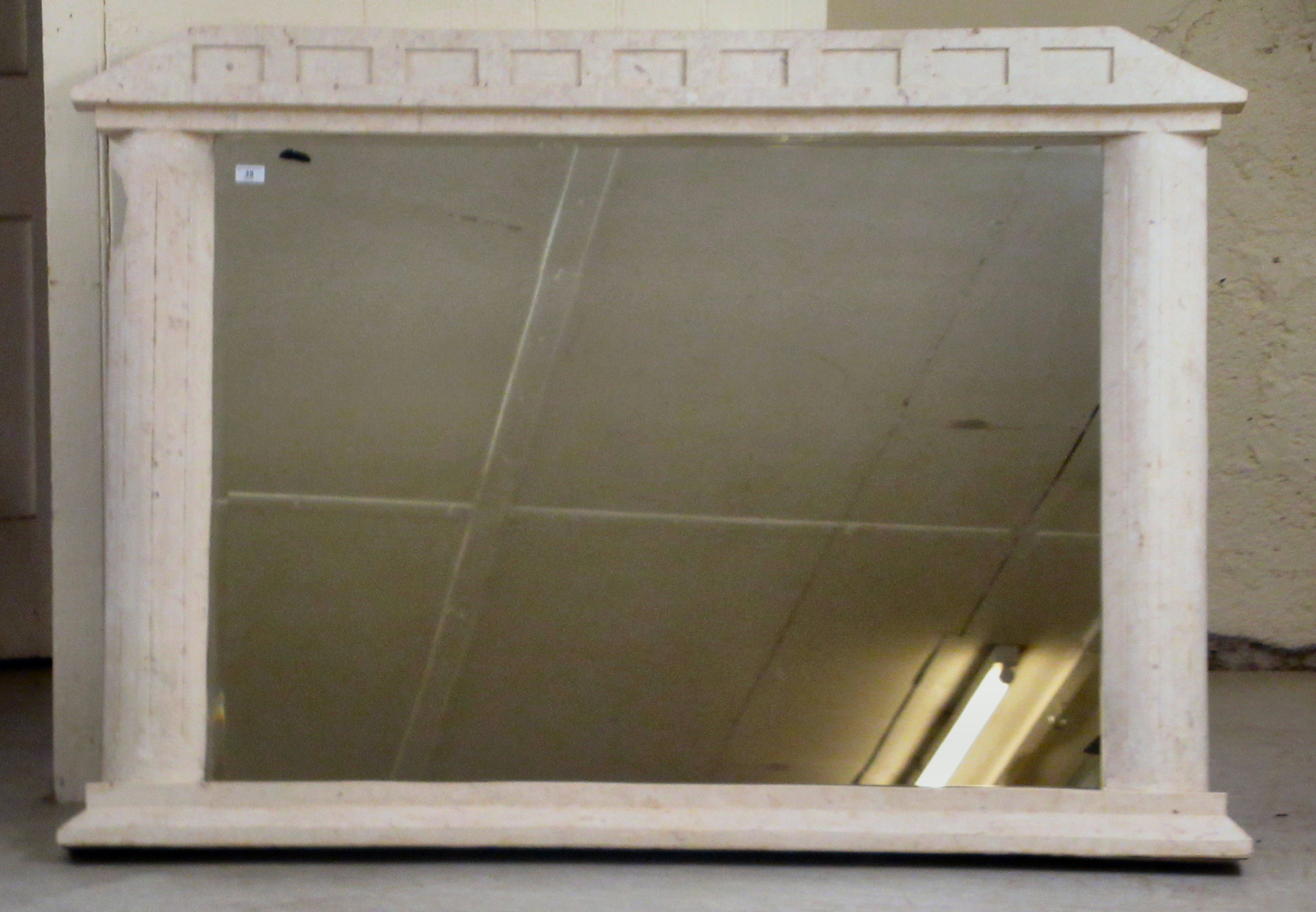A modern overmantel mirror, the bevelled plate set in a weathered stone effect composition framed