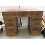 A late Victorian oak desk, the top set with a gilded red hide scriber, over foliate and lion mask