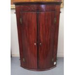 A George III satinwood and ebony inlaid mahogany quadrant corner cupboard with two panelled doors on