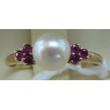 A 9ct gold ring, set with a pearl, flanked by six small rubies