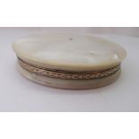 A circular mother-of-pearl two part powder box with a finely engraved yellow metal band