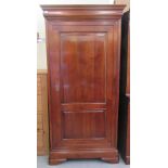 A modern cherrywood armoire with a moulded cornice, over a full height, twin panelled door, raised