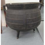 A black painted cast iron cauldron with opposing, angular loop handles and a flared rim, elevated on