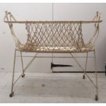 A late Victorian/Edwardian baby's cream painted wrought iron framed folding bassinet, incorporating