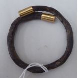 A 19thC roughwood bangle with gold coloured caps