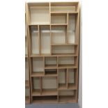 A modern light oak display unit with an arrangement of open shelves, on a plinth  87"h  41"w