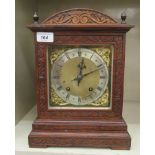 An early 20thC carved oak cased mantel clock with turned finials and a glazed window; the chiming