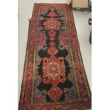 A Persian runner, decorated with stylised designs, on a dark blue coloured ground  42" x 118"