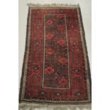 A Persian rug, decorated with repeating, stylised designs, on a red ground  38" x 78"