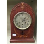 An Edwardian mahogany lancet top mantel clock with marquetry and inlaid brass ornament; the 8 day