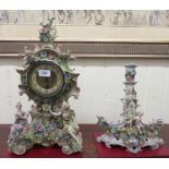 A 19thC porcelain clock, encrusted with flora and surmounted by figures; the movement faced by an