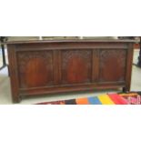 An early 20thC stained, tri-panelled oak coffer with straight sides and a hinged lid, raised on