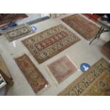 Five various woollen rugs: to include one decorated with geometric forms on a rust coloured