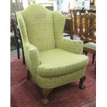 An early 20thC small Queen Anne style wingback armchair, upholstered in patterned green fabric,
