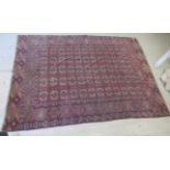 A Bokhara rug, decorated with five columns of twelve guls, bordered by repeating stylised designs,
