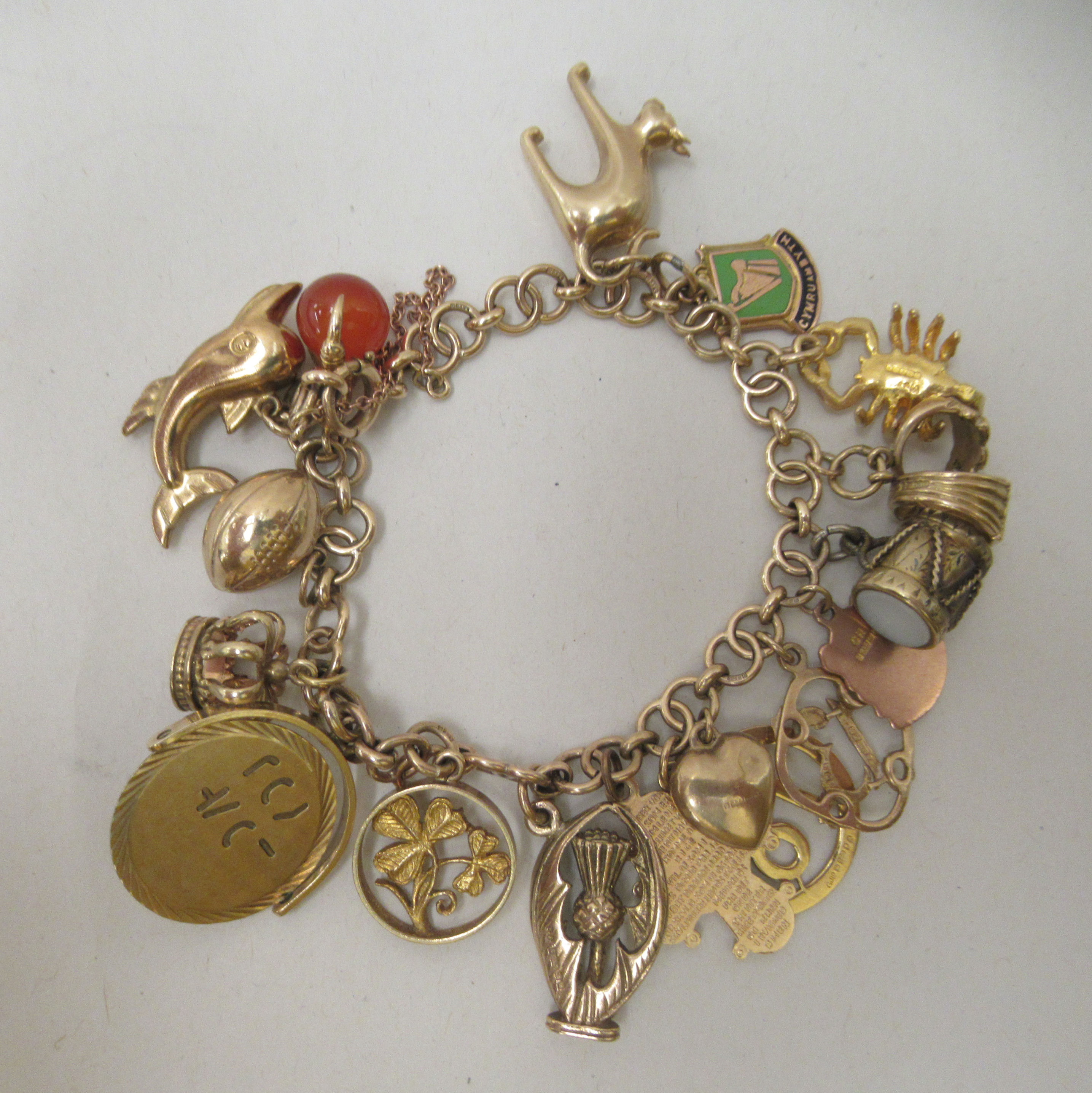 A 9ct gold and yellow metal charm bracelet with various charms