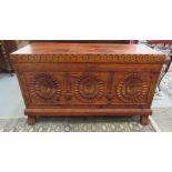 A modern stained pine chest with a hinged lid and carved, panelled front, raised on block legs  24"h
