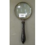 A lacquered brass magnifying glass, on a turned wooden handle