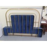 An iron framed and part gilt painted bedhead, incorporating a cushioned and braided midnight blue