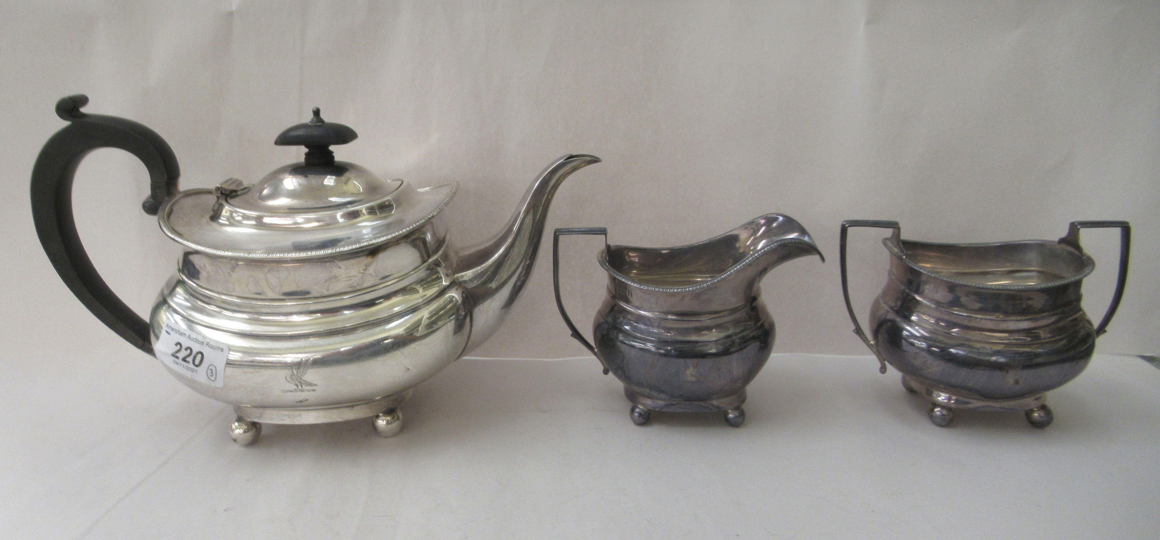 A George V silver three piece tea set  comprising a teapot, a cream jug and sugar basin