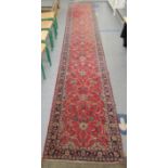 A Persian runner, decorated with repeating floral and foliage designs, on a red ground  29" x 132"