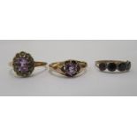 Three yellow metal rings, variously set with purple stones