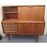 A Younger teak sideboard with an arrangement of open shelves, a fall flap, four drawers and a pair