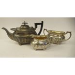 An Edwardian three piece silver tea set of bulbous, oval form with embossed demi-reeded and stop-