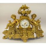 A late 19thC gilded metal cased mantle clock, surmounted by an urn, a pair of doves, fruiting vine