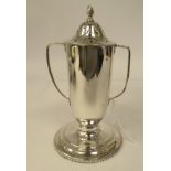 A silver caster of twin handled trophy vase form with a decoratively pierced cover and frame finial,