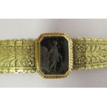 A gold coloured metal floral and foliate engraved flexible, tapered, tablet link bracelet, on a