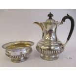 An Edwardian silver teapot of squat, bulbous and waisted, demi-reeded form with gadrooned borders,