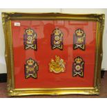 A display of five British Foot Guards bullion badges, displayed around the Royal coat of arms