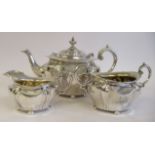 An Edwardian three piece silver tea set of oval, panelled, bulbous form  comprising a teapot, having