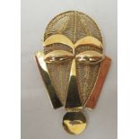 An African gold brooch, fashioned as a tribal mask with filigree ornament  stamped 18ct